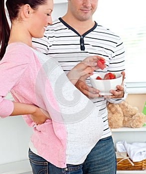 Delighted pregnant woman eating strawberries