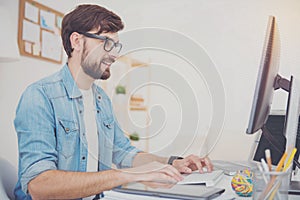 Delighted programmer in glasses using a computer