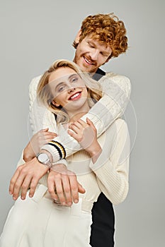 delighted redhead man embracing fashionable blonde