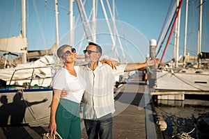 Delighted senior man showcasing newly acquired yacht to wife outdoor