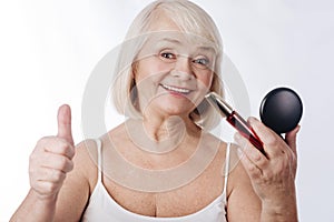 Delighted senior woman holding mascara