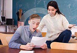 Delighted teenager and Chinese girl schoolmate reading notification