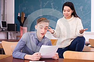 Delighted teenager and Chinese girl schoolmate reading notification