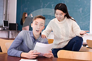 Delighted teenager and Chinese girl schoolmate reading notification