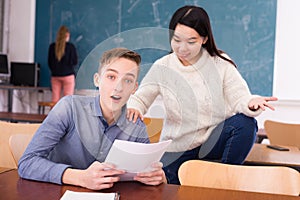 Delighted teenager and Chinese girl schoolmate reading notification photo