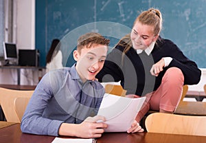 Delighted teenager and female schoolmate reading notification photo