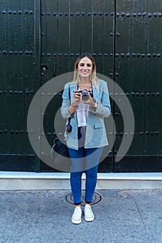 Delighted woman with retro camera in city