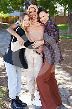 Delighted young diverse girls embracing and smiling in park