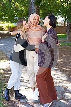 Delighted young diverse women embracing and smiling in park