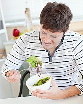 Delighted young man eating a healthy salad