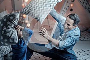 Delighted young man fighting with pillows