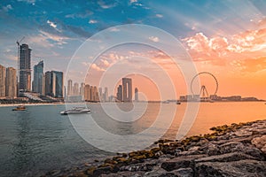 Delightful and colorful sunset over Blue waters Island with the famous Dubai Eye Ferris wheel. Panoramic view of the city in UAE
