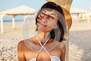 Delightful girl enjoying her holiday at sea. Happy beautiful young woman smiling on the beach