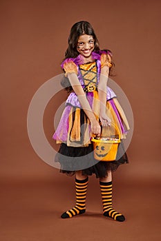 delightful girl in Halloween costume holding