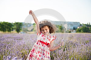 Delightful happy smiling little girl with bouquet of flowers in lavender field