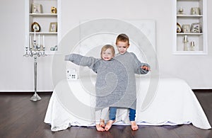 Delightful little children in big grey sweater.