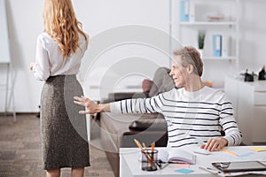 Delightful mature office manager touching young colleague body at work photo