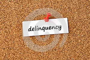 Delinquency. Word written on a piece of paper, cork board background