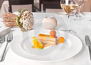 Delis foie gras and mango with white wine glass on a restaurant table