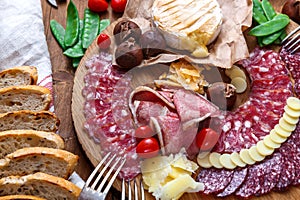 Delisious snacks on wooden board: sausages, bread, cheese, chestnuts and beer. Close view.