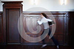 Deliver the documents to the laywer in time. Blurred motion view a female legal person running while carrying some