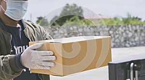 Deliver man wearing face mask with handling paper box for deliver to customer in the door at home, concept of new normal, corana v