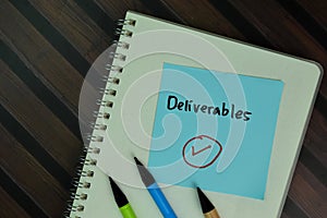 Deliverables write on sticky notes isolated on Wooden Table