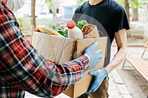 Delivering food to senior citizens in quarantine during Covid-19 Coronavirus epidemic. Courier in black shirt medical gloves