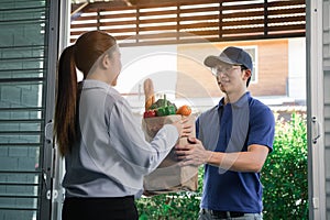 Delivery of an asian man handling a bag of food to a female customer at the door