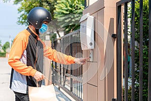 Delivery Asian man wear protective mask in orange uniform and ready to send delivering Food bag in front of customer houes with
