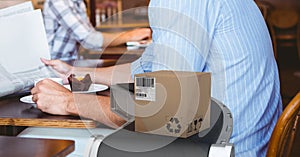 Delivery box over a conveyer belt against mid section of a person drinking coffee in a cafe