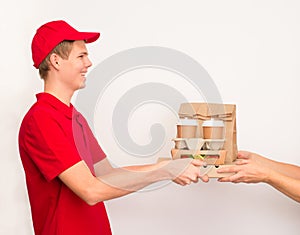 Delivery boy giving food order and holding pizza box salad disposable paper cups and paper bag over white background