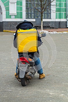 Delivery boy of takeaway on scooter with isothermal food case box. Express food delivery service from cafes and restaurants.