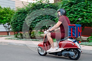 Delivery boy wearing red uniform on scooter with isothermal food case box driving fast. Express food delivery service