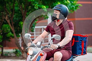 Delivery boy wearing red uniform on scooter with isothermal food case box driving fast. Express food delivery service