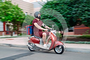 Delivery boy wearing red uniform on scooter with isothermal food case box driving fast. Express food delivery service