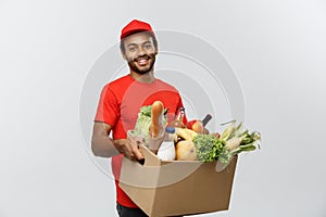 Delivery Concept - Handsome African American delivery man carrying package box of grocery food and drink from store