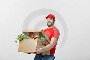 Delivery Concept - Handsome Cacasian delivery man carrying package box of grocery food and drink from store. Isolated on