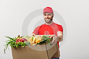 Delivery Concept - Handsome Cacasian delivery man carrying package box of grocery food and drink from store. Isolated on