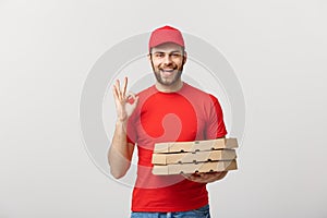 Delivery Concept: Handsome pizza delivery man making OK sign isolated over grey background.