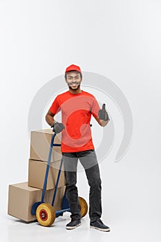 Delivery Concept - Portrait of Handsome African American delivery man or courier pushing hand truck with stack of boxes