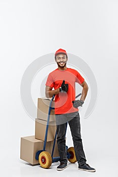 Delivery Concept - Portrait of Handsome African American delivery man or courier pushing hand truck with stack of boxes