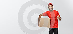 Delivery Concept - Portrait of Happy African American delivery man holding a box package and showing thumps up. Isolated