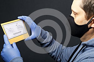 Delivery of correspondence during the period of self-isolation. A man in rubber gloves and and a mask holding a delivered letter