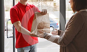 Delivery with courier at home. Deliveryman gives paper package to girl client