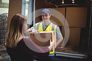 Delivery driver handing parcel to customer outside van