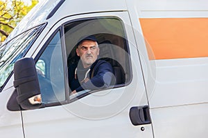 Delivery driver looking out the window of the white cargo van vehicle, delivering goods by car