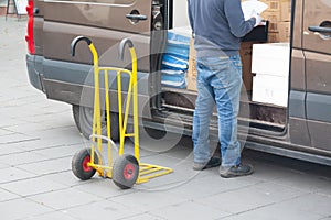 Delivery driver is unloading cargo van with goods to truck