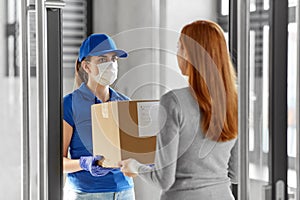 Delivery girl in face mask giving parcel to woman