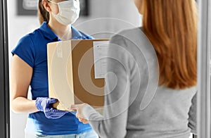 Delivery girl in face mask giving parcel to woman